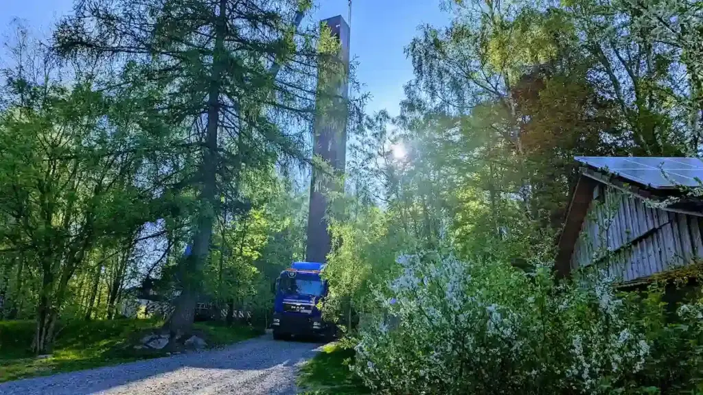 Ein LKW-Kran von energystation dreht einen tonnenschweren Stahlkubus in der Luft, um ihn punktgenau auf den Turm zu setzen.