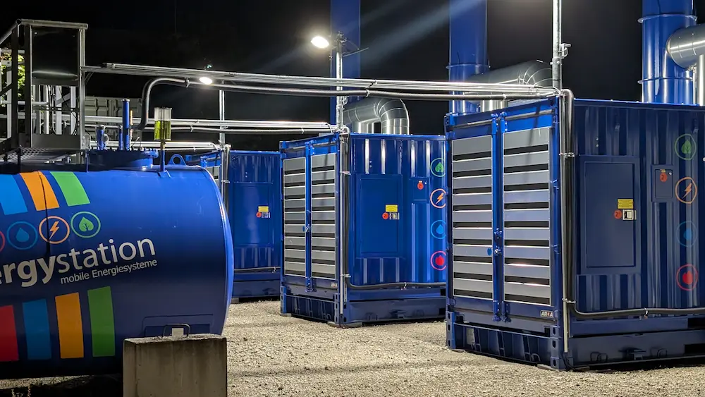 Hybrides Stromversorgungs-Setup von energystation mit mehreren verbundenen Aggregaten und Kraftstofftank bei Nacht